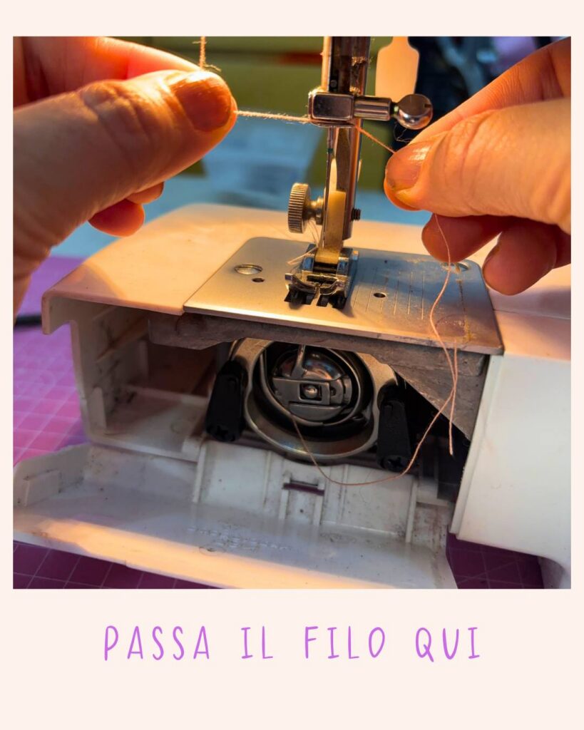 Vista frontale della macchina da cucire con il filo che scende lungo la barra ago verso il piedino