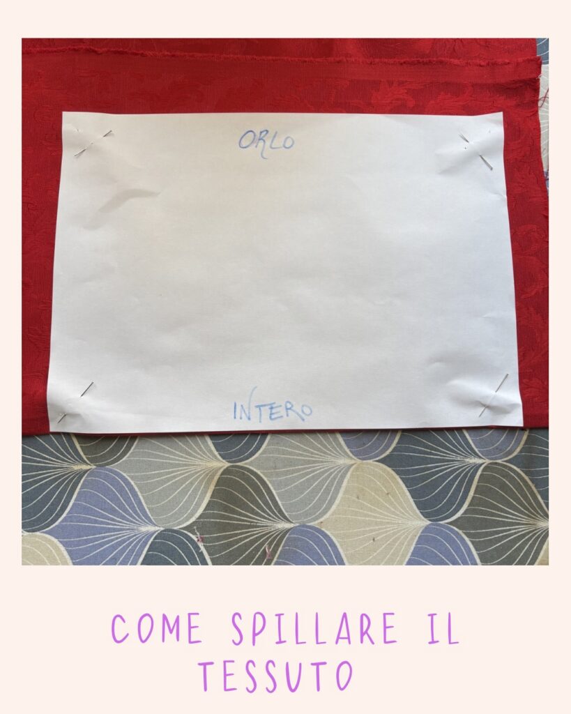 Cartamodello spillato su tessuto rosso con spilli ai bordi