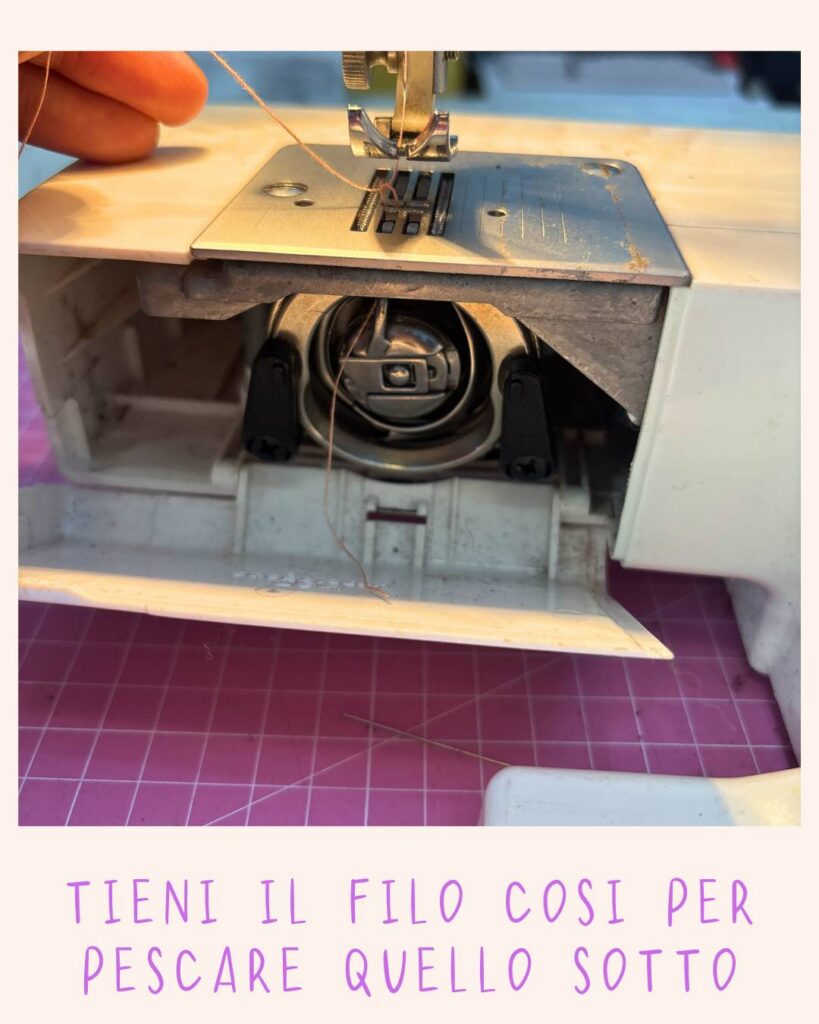 Mani che tengono il filo superiore teso per far emergere il filo inferiore della bobina dal foro della placca ago