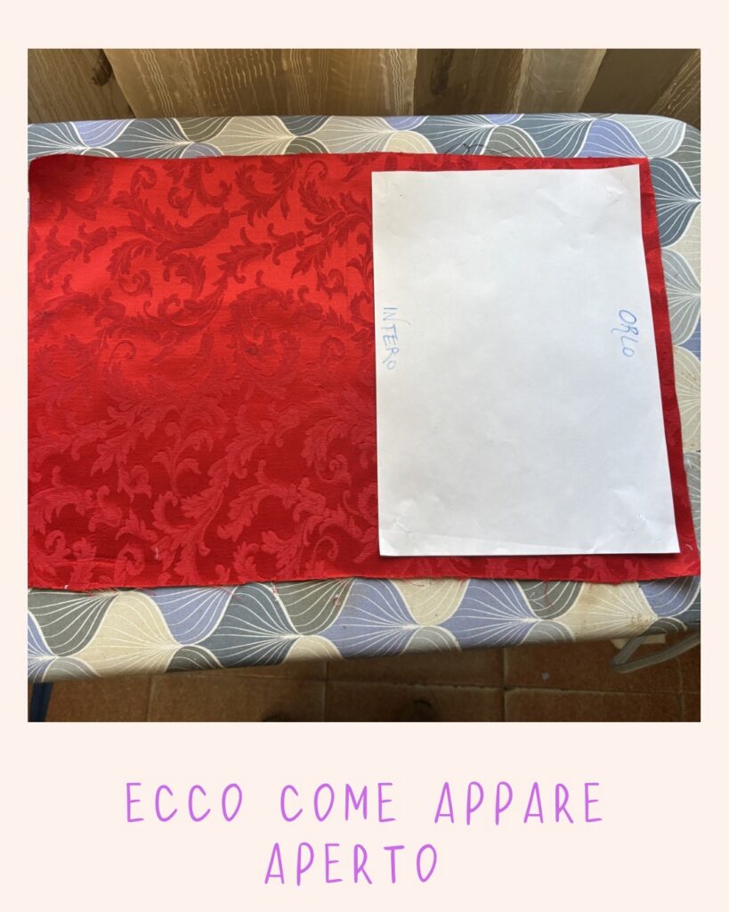 Tessuto rosso e cartamodello aperti sul tavolo da stiro