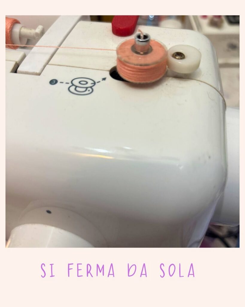 Bobina di filo arancione completamente avvolta sul perno della macchina da cucire