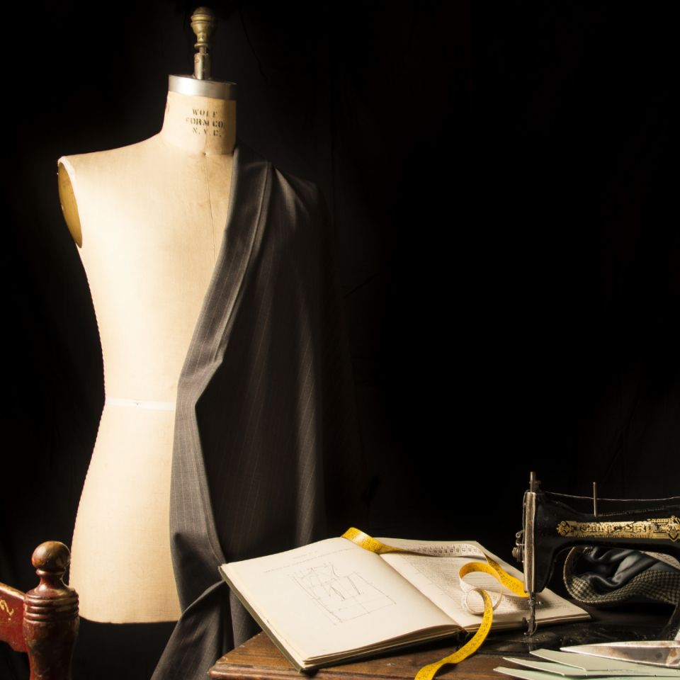 Manichino che indossa giacca scura e macchina da cucire antica