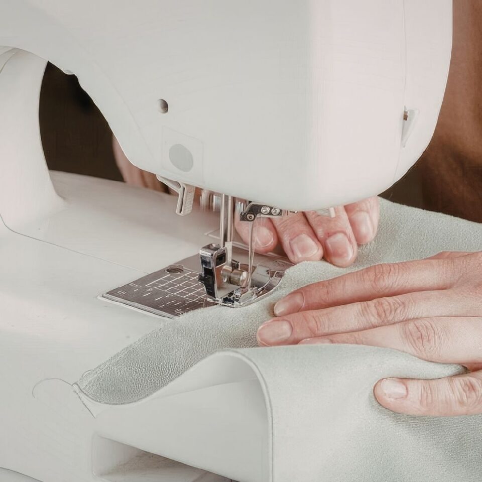 Mani che guidano il tessuto sotto il piedino della macchina da cucire
