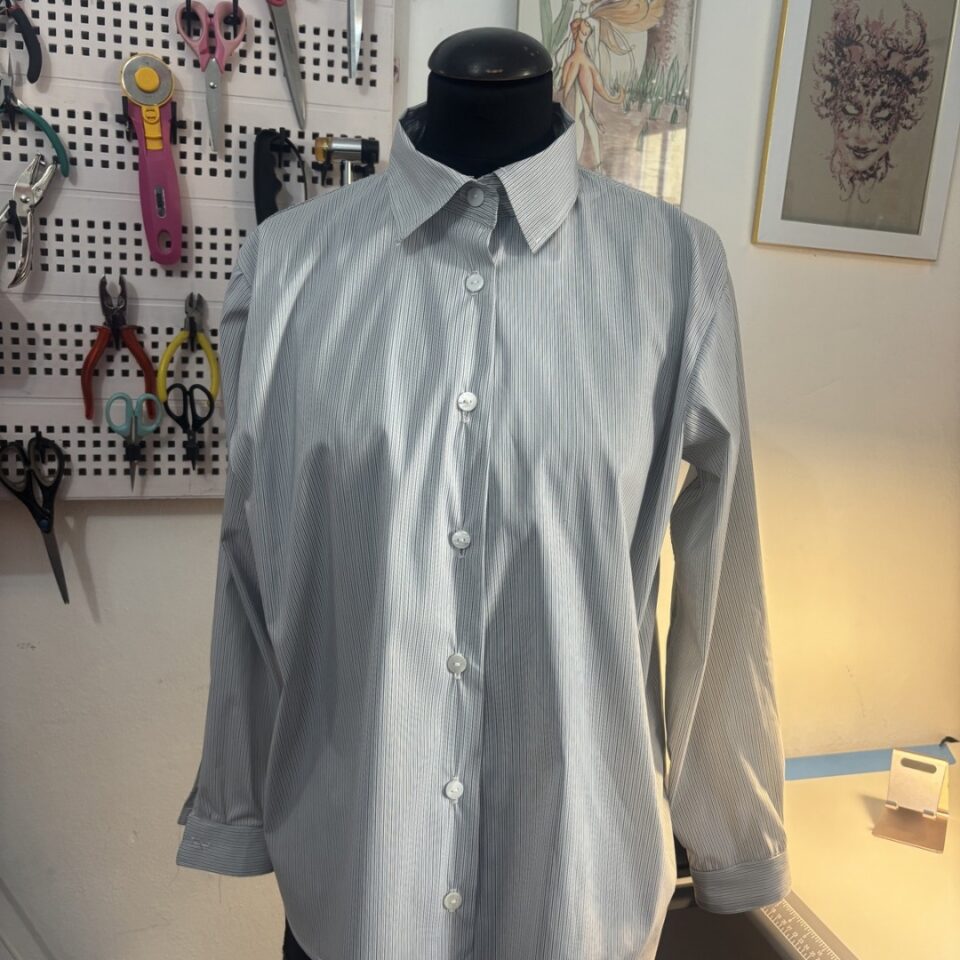 Una camicia da donna grigia a righe su manichino nel laboratorio di sartoria